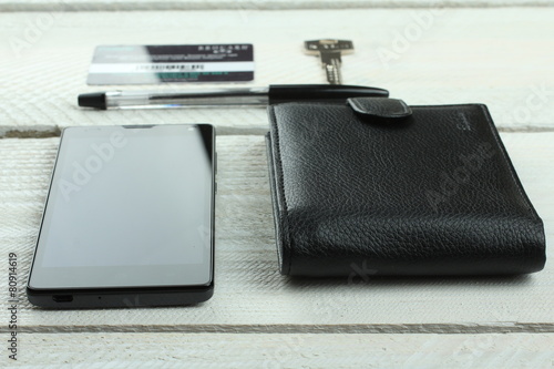 Men's wallet, phone, keys and card on wooden table