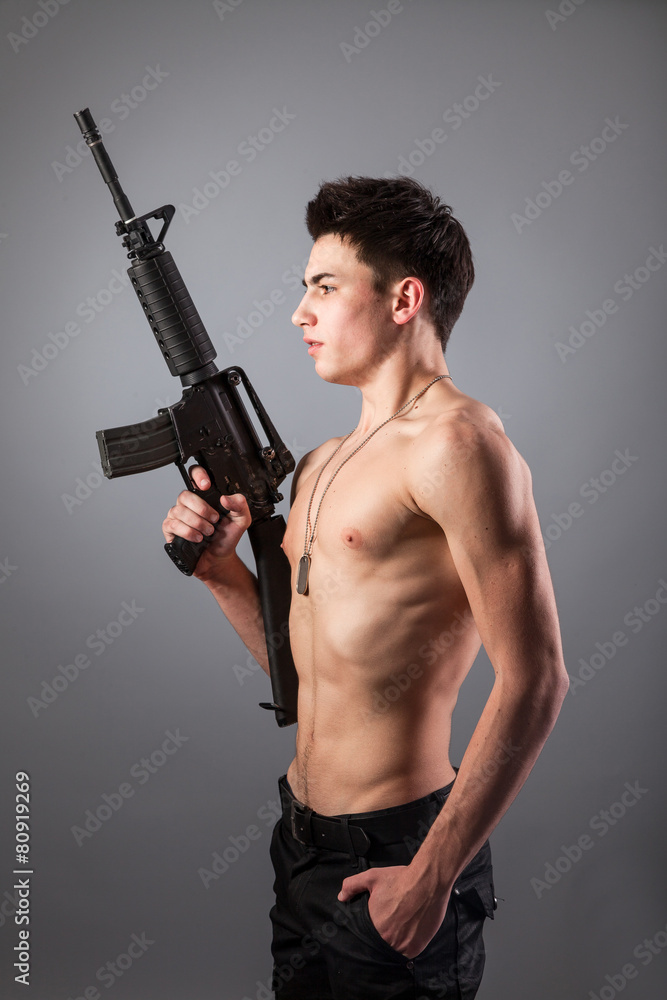 Handsome bare-chested soldier is holding a rifle Handsome bare-chested soldier is holding a rifle