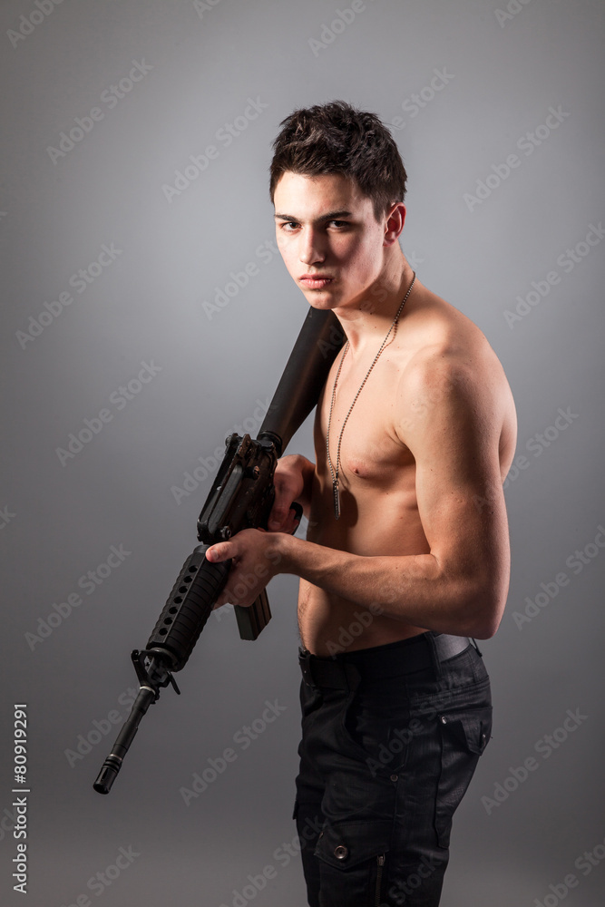 Handsome bare-chested soldier is holding a rifle Handsome bare-chested soldier is holding a rifle