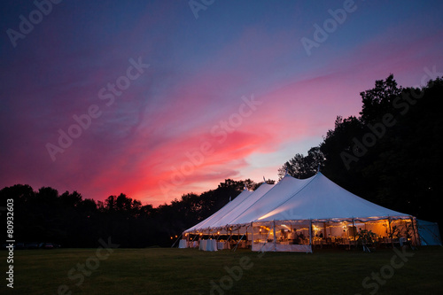 An event tent at night with a sunset during a wedding