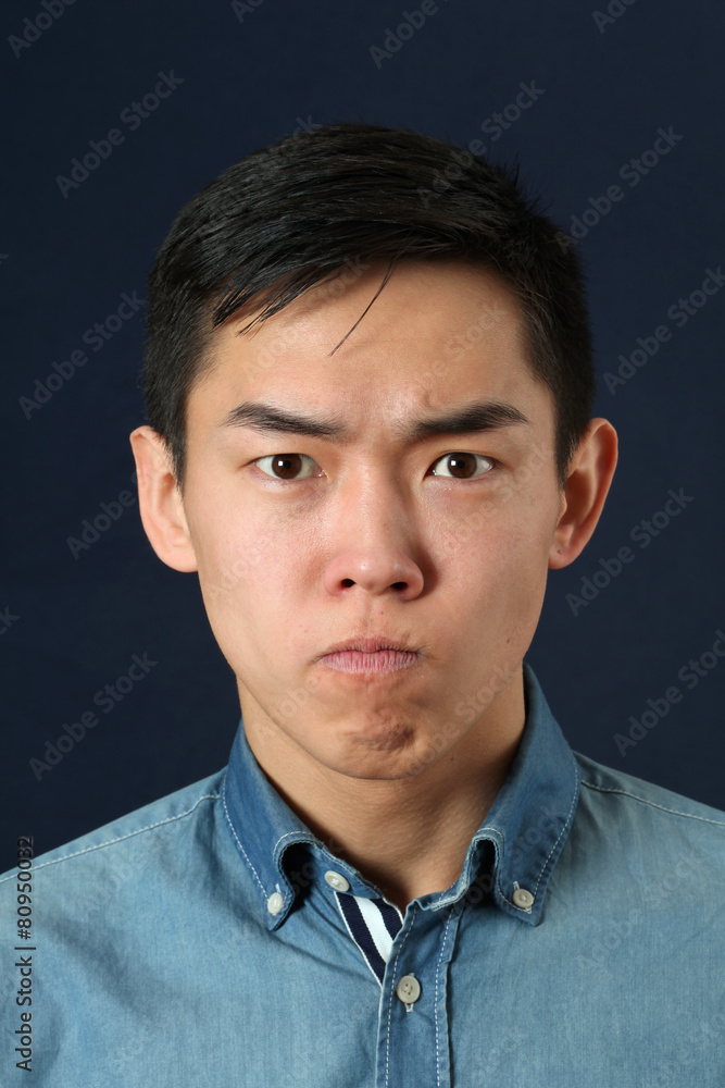 Displeased young Asian man looking at camera Displeased young Asian man looking at camera