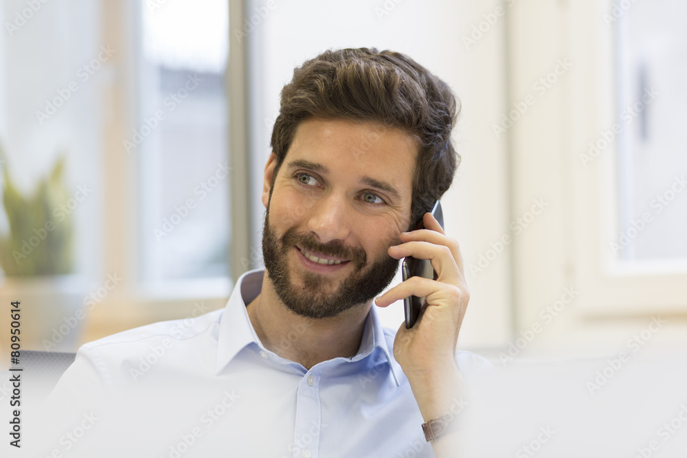 Cheerful Hipster man in office. Typing text on mobile phone Cheerful Hipster man in office. Typing text on mobile phone