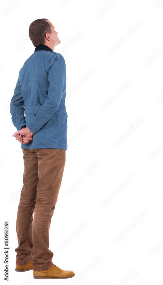 Fototapeta premium Back view stylishly dressed man in a brown jacket looking up.