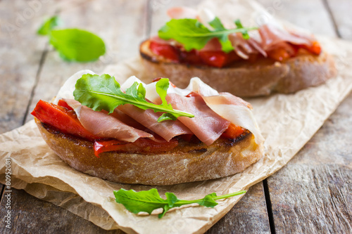 Obraz na płótnie bruschetta with roasted peppers, prosciutto and arugula