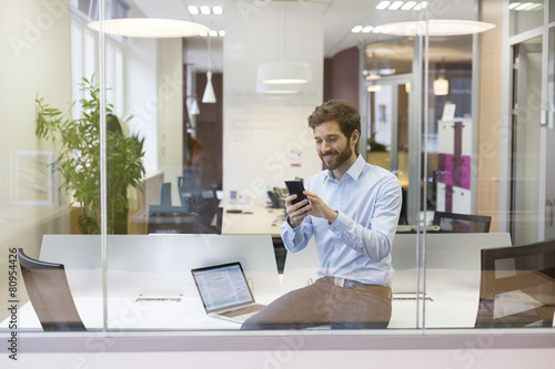 Hipster casual man.Typing text message on mobile phone in office