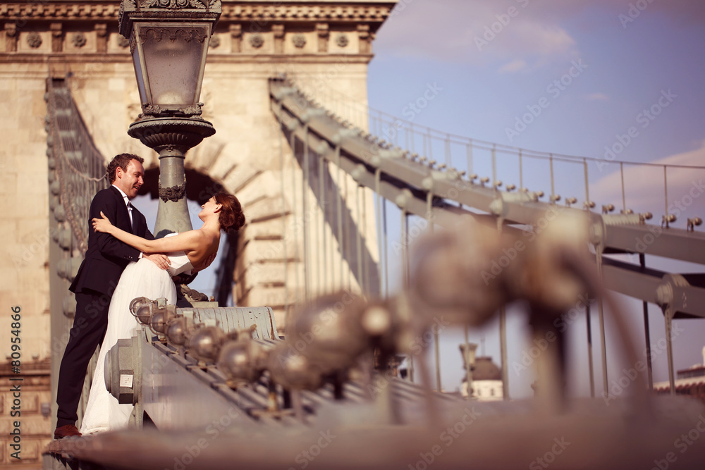 Bride and groom having fun on a bridge