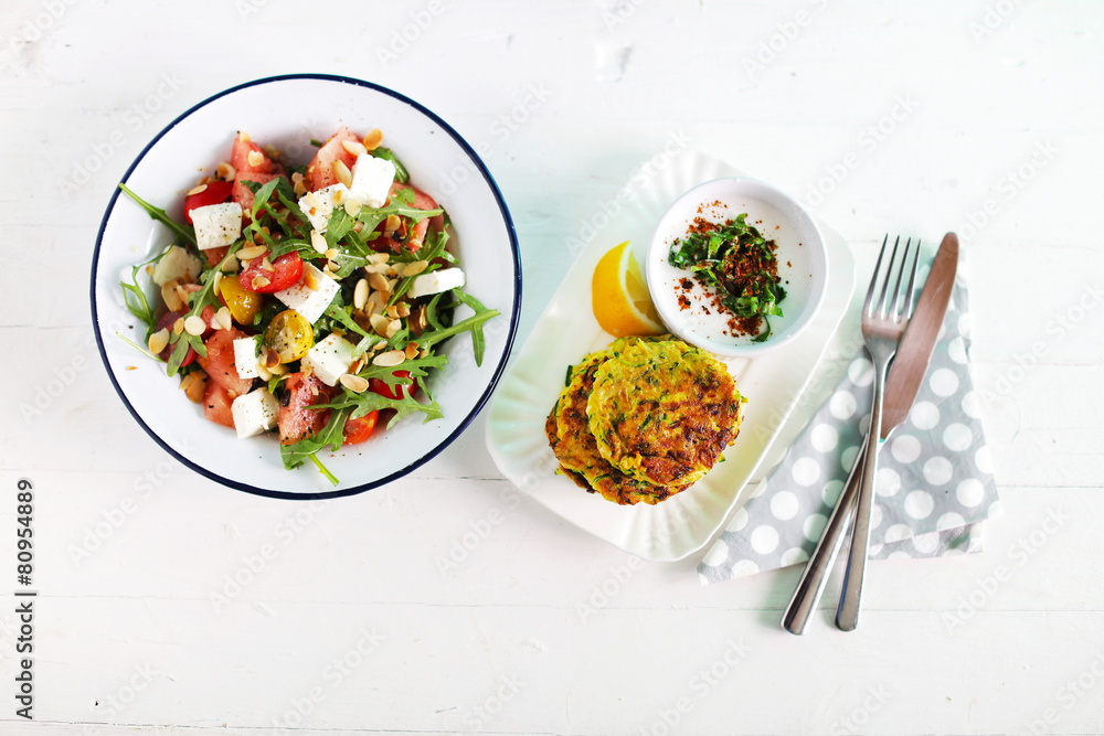 Watermelon salad with feta cheese and arugula, zucchini fritters