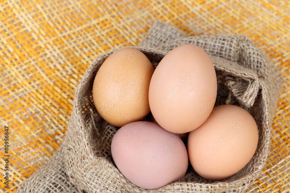 Chicken brown eggs in sack bag over bamboo weave background. Chicken brown eggs in sack bag over bamboo weave background.