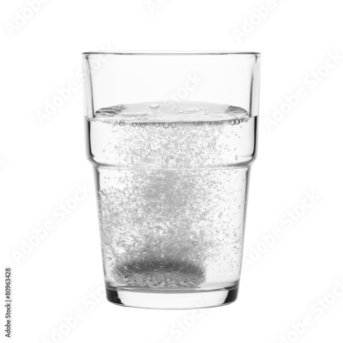 Fizzy tablet in glass of water isolated on white