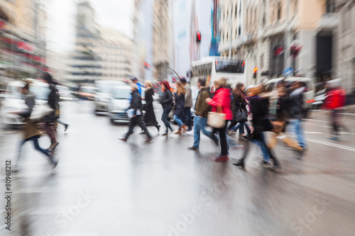 Menschenmenge überquert nasse Straße mit Zoomeffekt