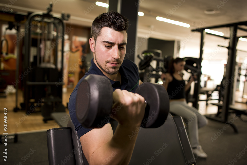 Young man training biceps at gym Young man training biceps at gym