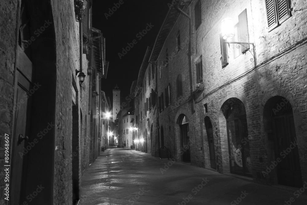 Black and white street scene in Italy at night. Italian street lit by street lamps
