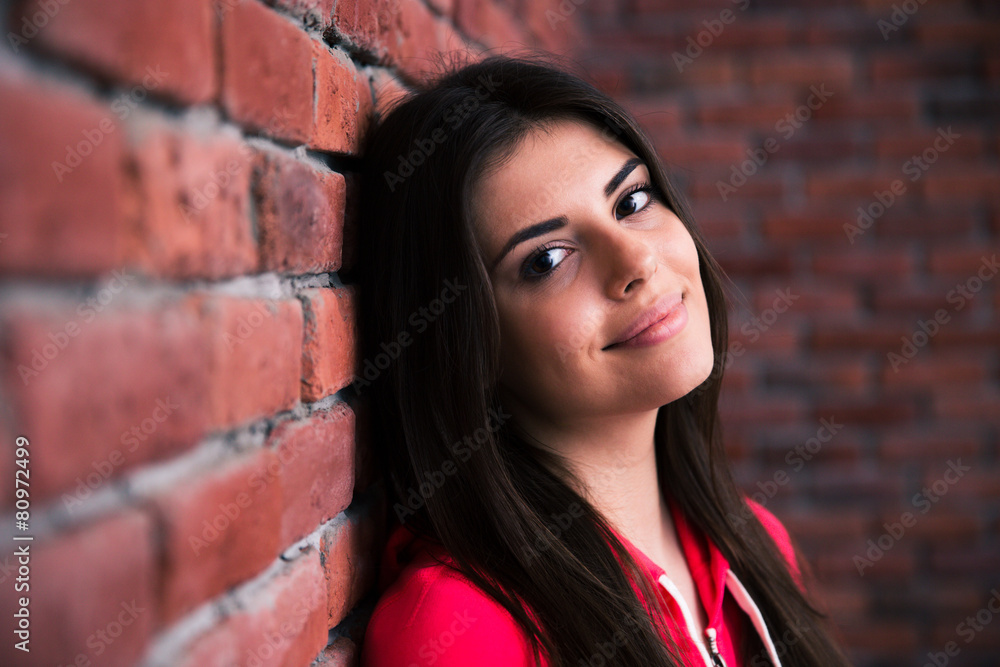 Closeup portrait of a happy woman leaning on the brick wall Closeup portrait of a happy woman leaning on the brick wall