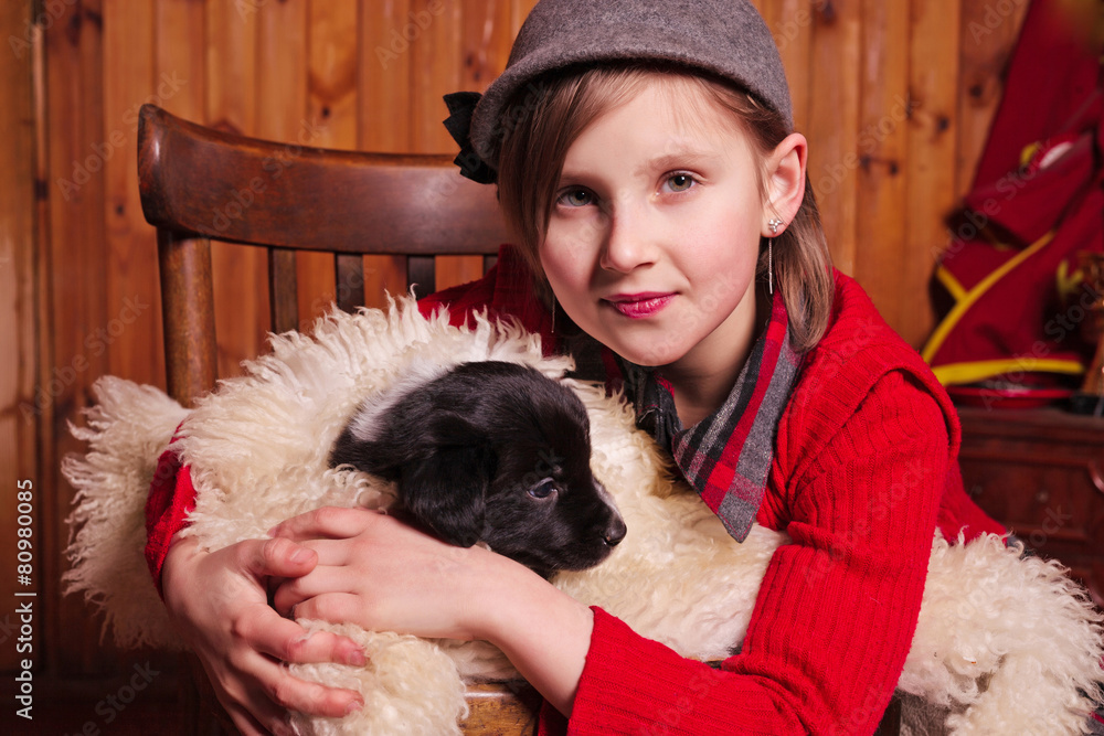 Φωτογραφία Young girl hugging a puppy wrapped in a sheepskin. Farm.