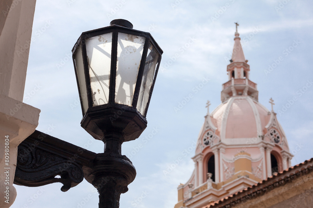 Antiguo farol en la ciudad amurallada de Cartagena de Indias con la famosa Catedral de Santa Catalina de Alejandría al fondo en Colombia