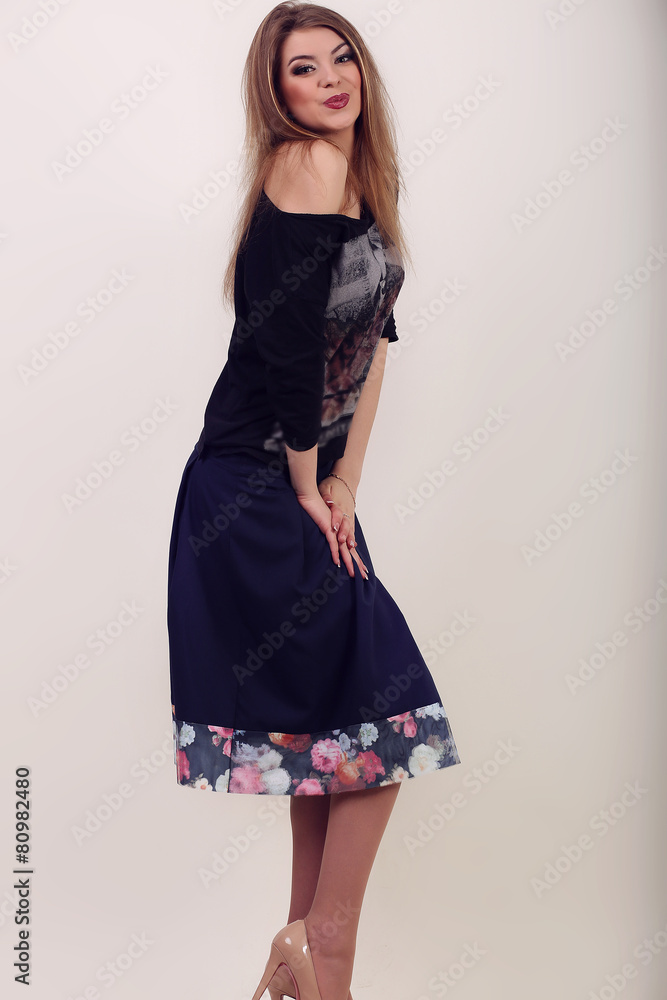 Fototapeta premium Young brunette lady in black dress posing on grey background