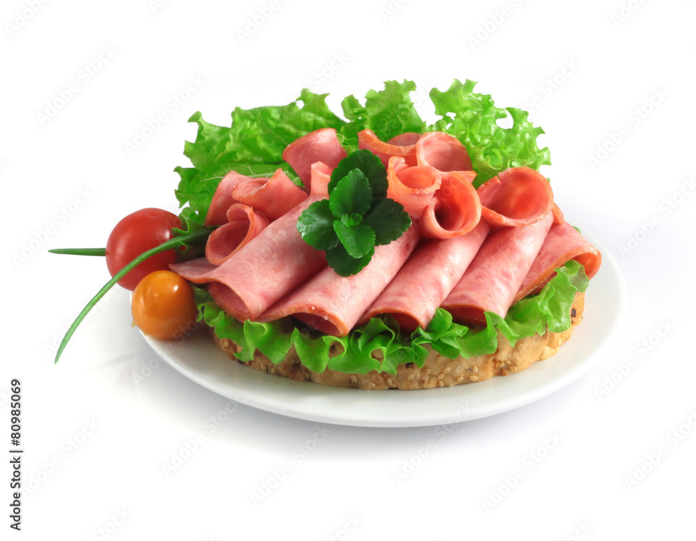 sliced sausage with herbs and vegetables on a white plate. sliced sausage with herbs and vegetables on a white plate.