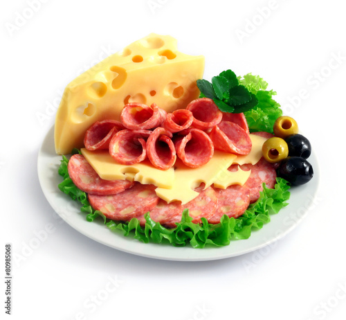 sliced sausage and cheese with herbs and olives on a white plate
