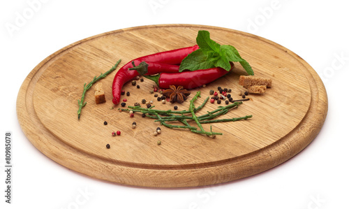 Chili pepper, herbs and spices on a wooden board.