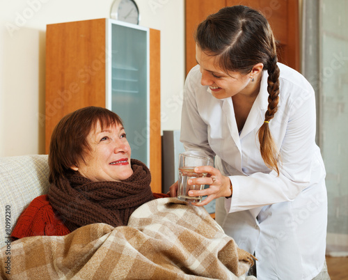  nurse giving glass of water to  mature woman