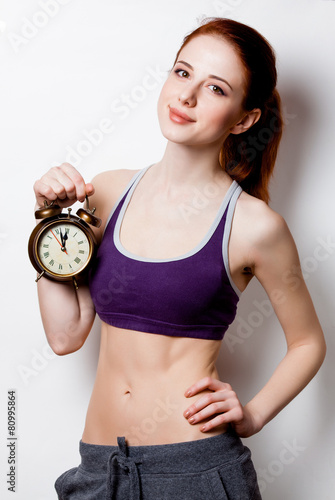 Woman showing her abs with alarm clock