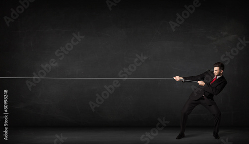 Businessman pulling rope on grey background