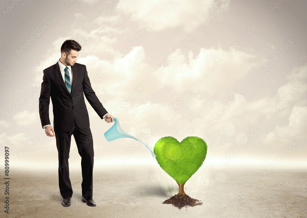 Business man watering heart shaped green tree Business man watering heart shaped green tree