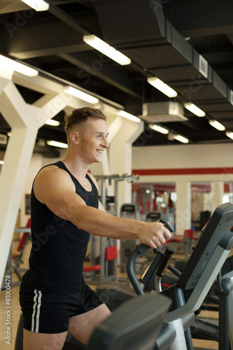 Merry young man exercising on treadmill
