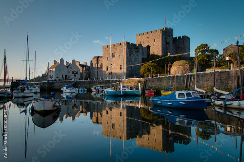 Sunrise at Castletown Harbor in the Isle of Man with Castle Rushen and boats reflecting in the water.