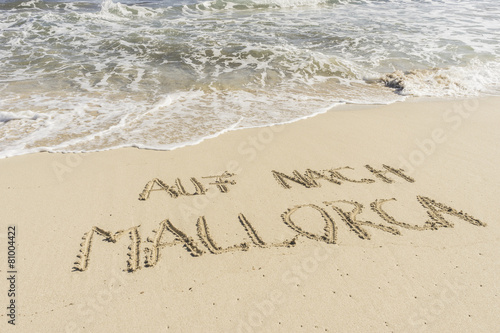 Text AUF NACH MALLORCA in Sand gezeichnet mit Wellen