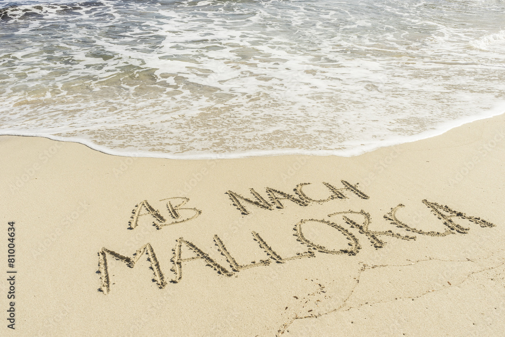 Fototapeta premium Text AB NACH MALLORCA in Sand gezeichnet mit Wellen