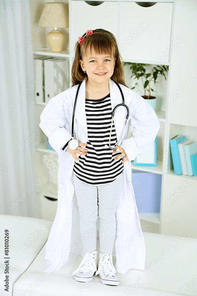 Little girl in doctor costume with stethoscope on office interior background
