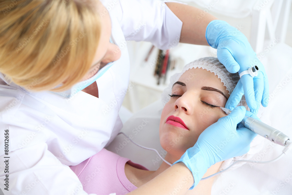 Cosmetologist applying permanent make up on eyes, close-up Cosmetologist applying permanent make up on eyes, close-up