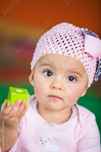 Bebita de seis meses jugando con un cubo en actitud pensativa photo