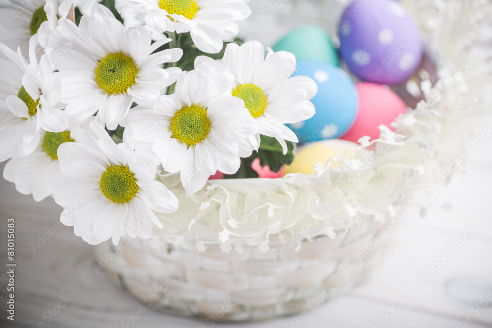 easter present basket with white flowers and colored eggs