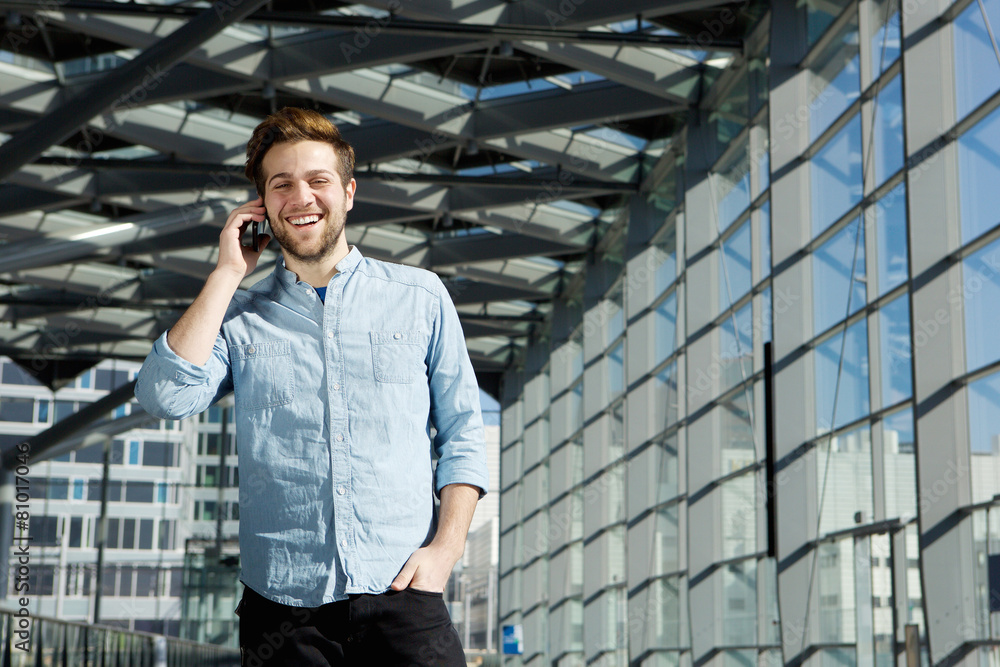 Young man smiling inside building with cell phone Young man smiling inside building with cell phone