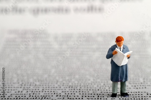 miniatura di uomo d' affari che legge il giornale