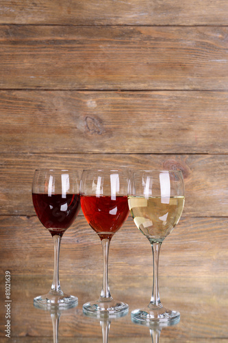Different glasses of wine on table on wooden background