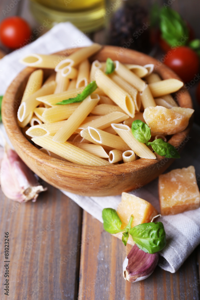 Raw pasta in bowl with cheese and vegetables on table close up Raw pasta in bowl with cheese and vegetables on table close up