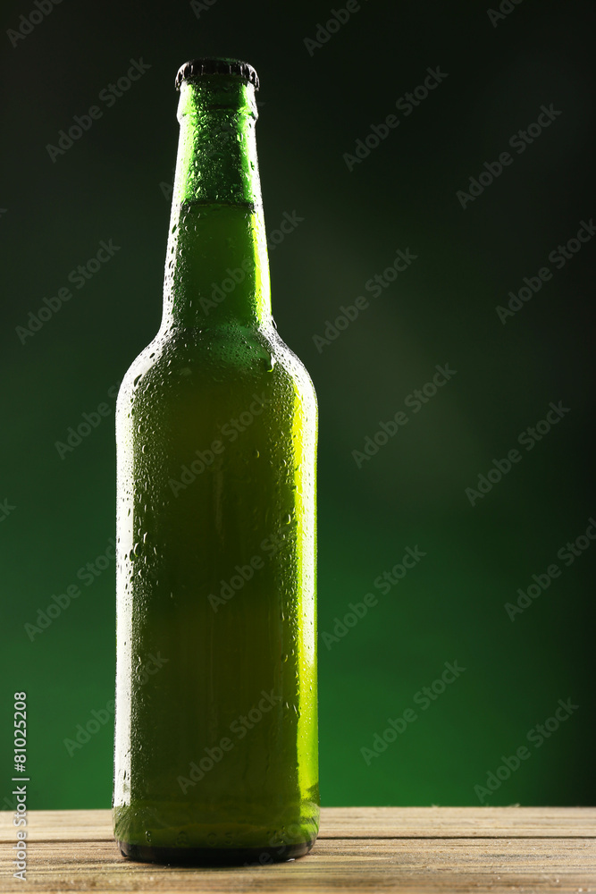 Glass bottle of beer on dark green background Glass bottle of beer on dark green background