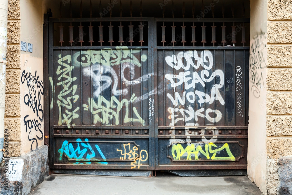 Old black locked gate with chaotic graffiti pattern Old black locked gate with chaotic graffiti pattern