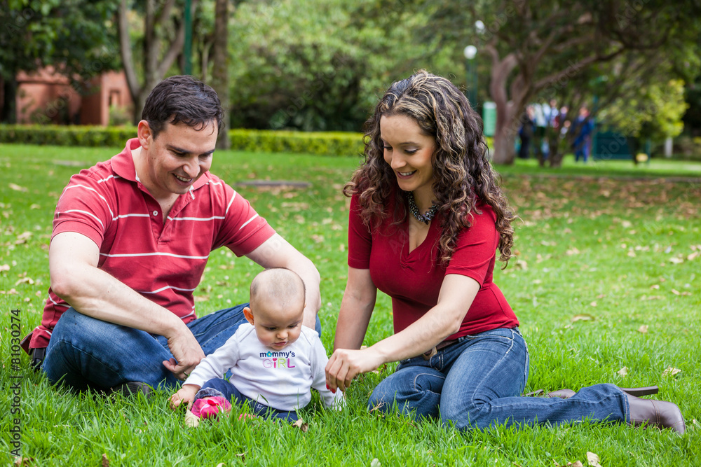 Pareja joven disfrutando de un hermoso día de sol con su bebita en un parque Pareja joven disfrutando de un hermoso día de sol con su bebita en un parque