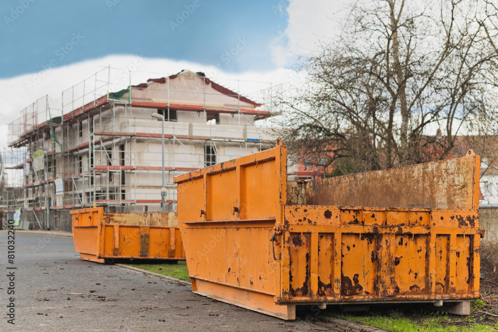 Fototapeta premium Grosse orange Container stehen vor einem Rohbau