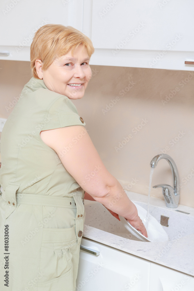 Woman washes dishes in the kitchen Woman washes dishes in the kitchen