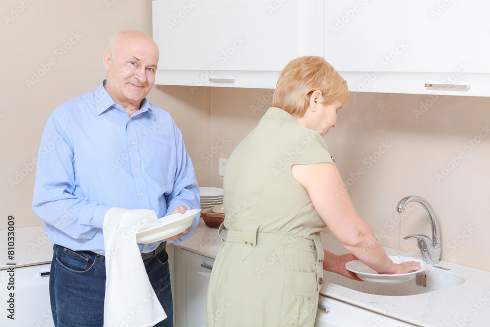 Fototapeta premium Couple washes dishes in the kitchen