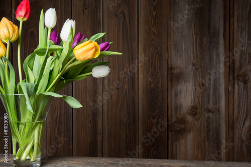 Colorful tulips in a vase on a wooden table