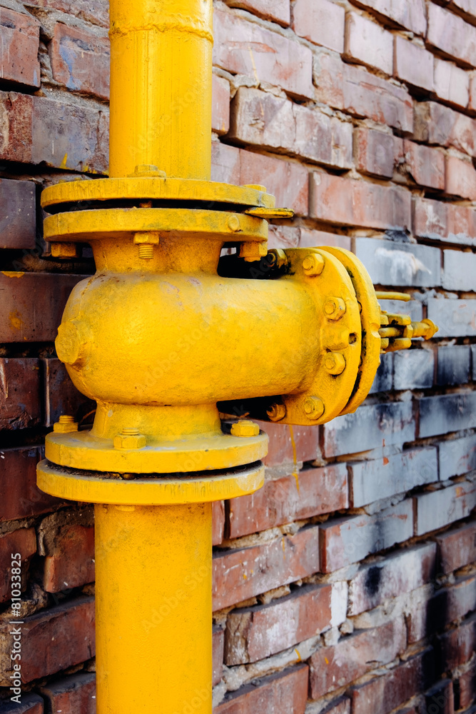 Yellow gas valve over red brick wall Yellow gas valve over red brick wall
