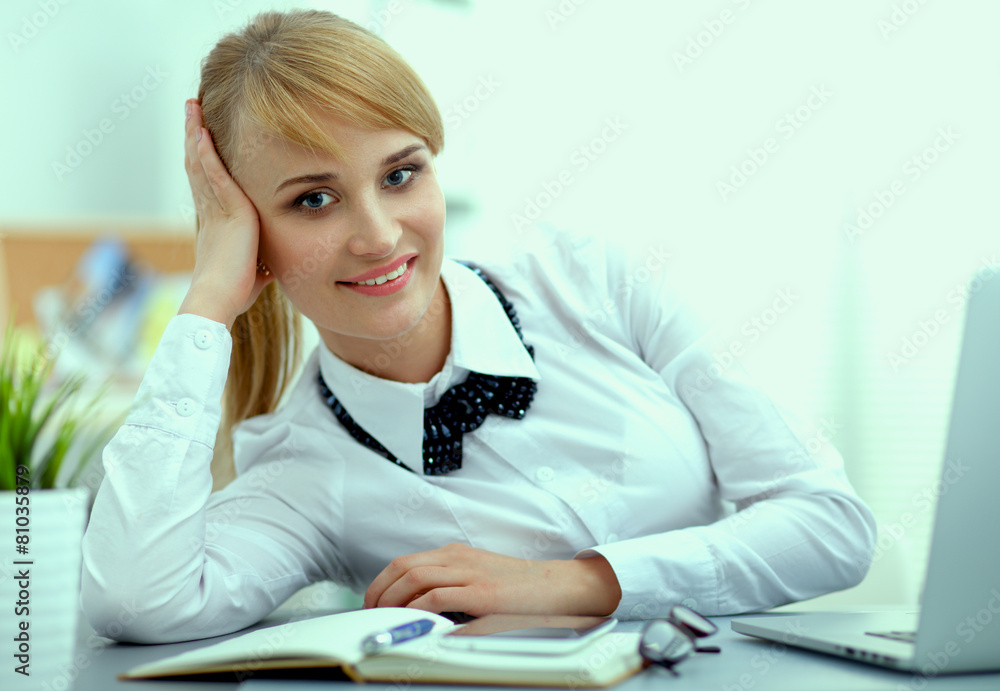 Fototapeta premium Portrait of businesswoman sitting at desk with a laptop