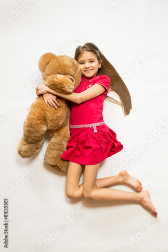 Isolated shot of cute smiling girl holing big brown teddy bear