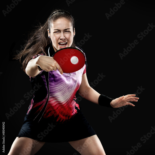 Young sports woman tennis-player in play on black background